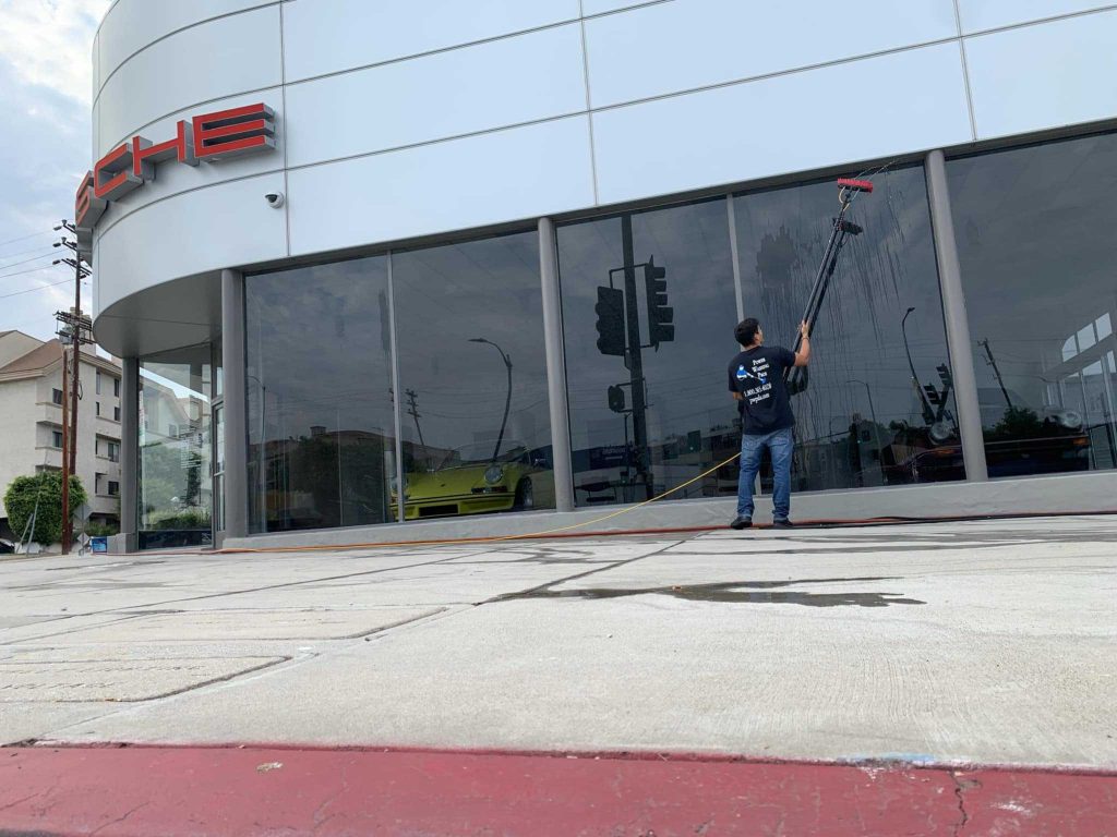 one of our staffs cleaning the storefront window to remove dust, cobwebs and loose dirt using pressure washing.