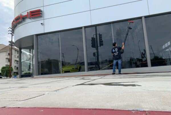 one of our staffs cleaning the storefront window to remove dust, cobwebs and loose dirt using pressure washing.