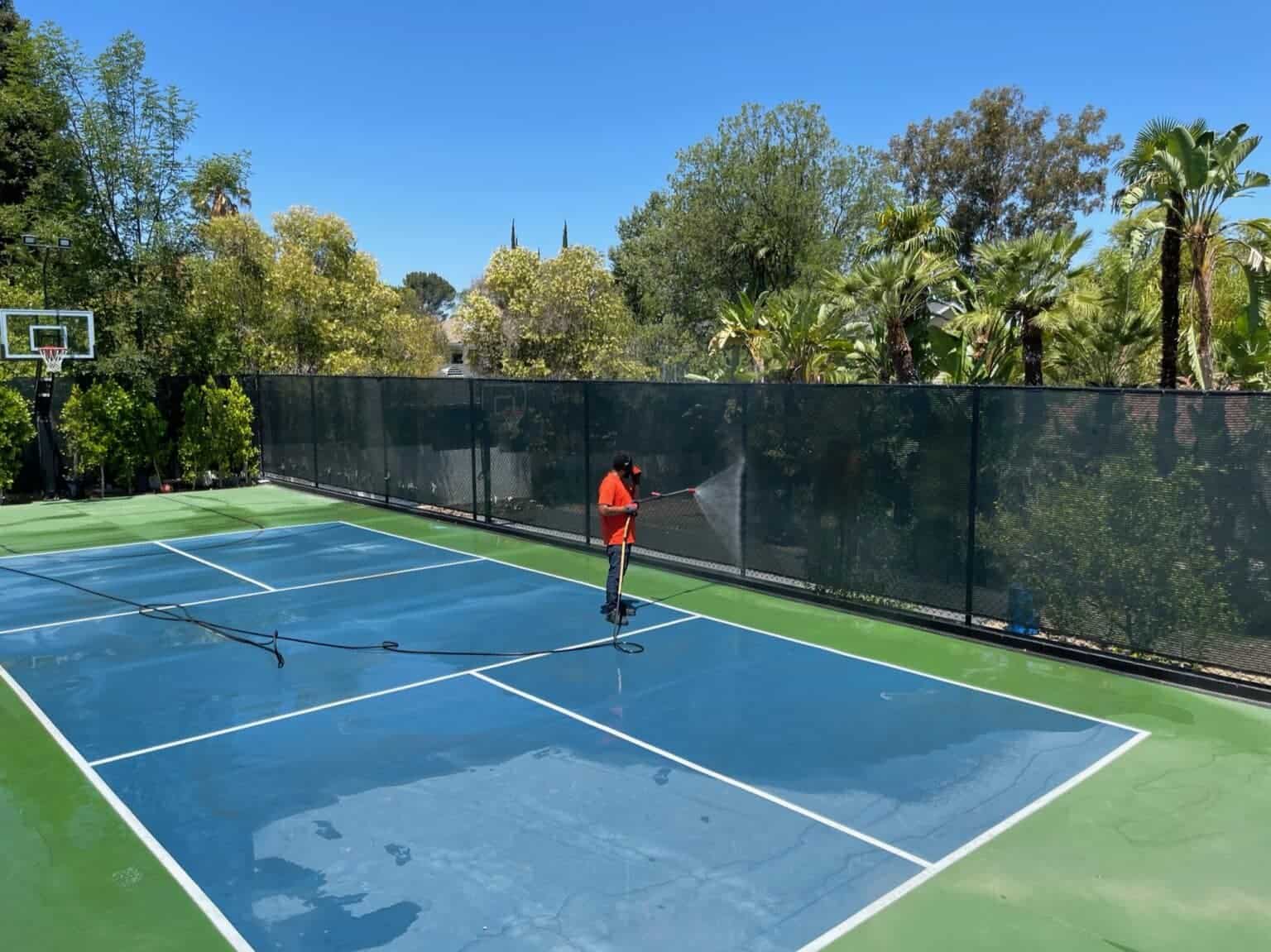 pressure washing the fence of a tennis court