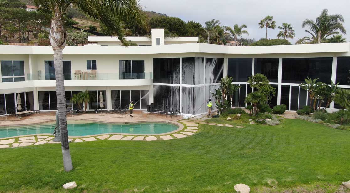 Applying detergent to a glass window to a mansion in los angeles