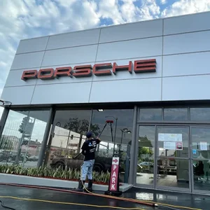 window cleaning the outside of a Porsche dealership