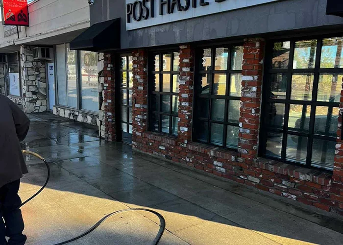 Cleaning the sidewalk at a strip mall with a power washer