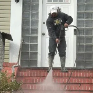 Cleaning Brick stairs with a power washer outside the entrance of a home